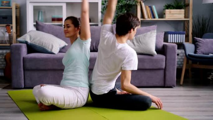 快乐的年轻夫妇一起做瑜伽，在配对中向后弯曲身体