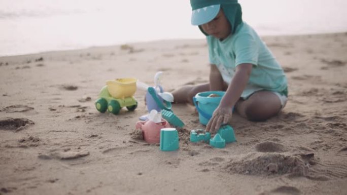 可爱的小男孩在沙滩上玩沙子。泰国。