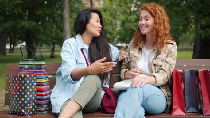 快乐的青少年用购物袋在公园的长凳上聊天的慢动作