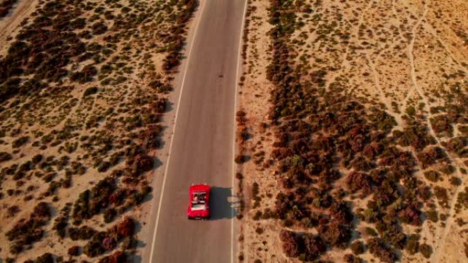 红色汽车在沙漠道路上行驶，鸟瞰图