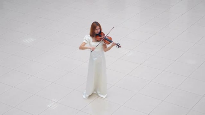 穿着白色连衣裙的女人站在白色瓷砖上拉小提琴