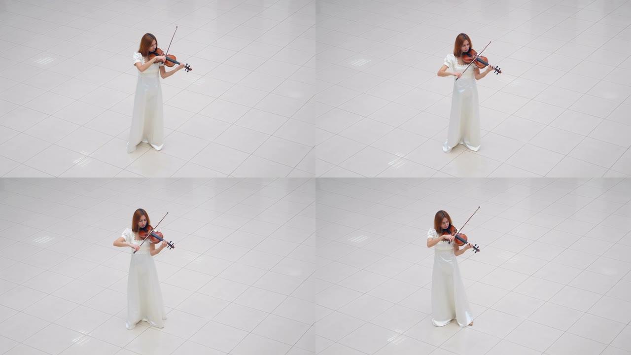 穿着白色连衣裙的女人站在白色瓷砖上拉小提琴