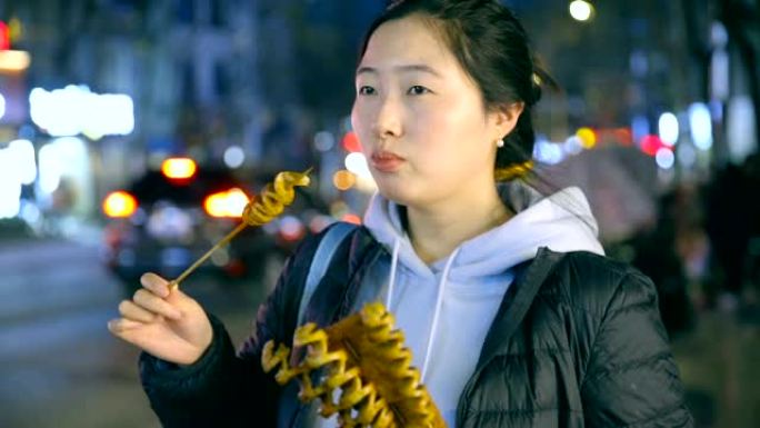 亚洲年轻女子晚上享受街头美食