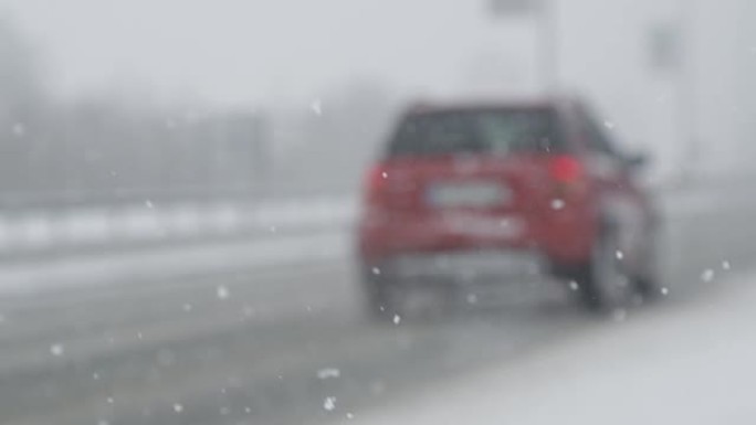 慢动作: 在下雪天，橙色汽车小心地沿着空旷的高速公路行驶。