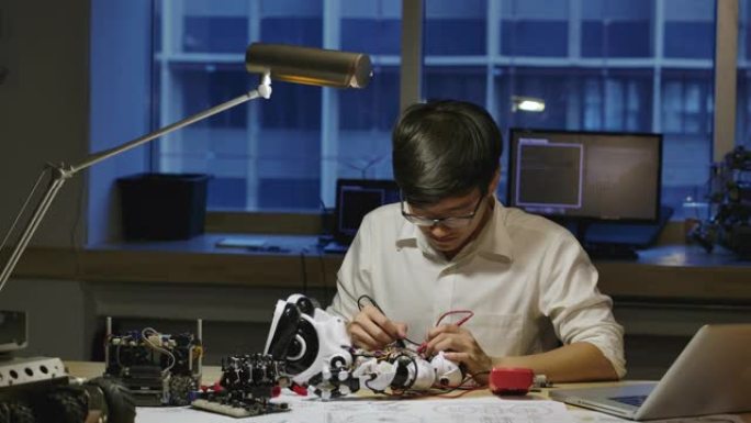 年轻的亚洲电子开发工程师在夜间在计算机科学研究实验室中建造，测试，固定机器人技术。有技术或创新概念的