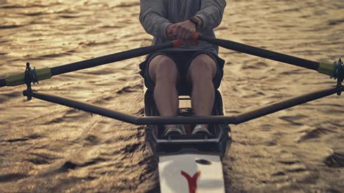 年轻的男运动员在日落时在河上划船