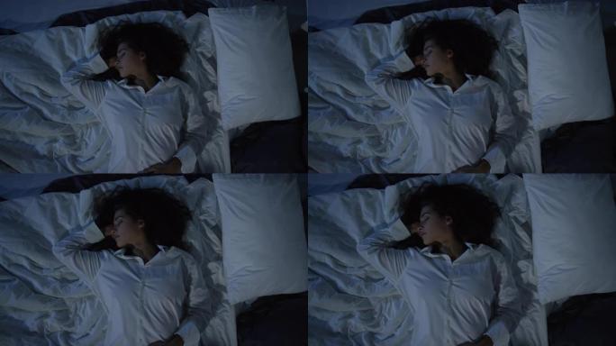 穿着男式衬衫的年轻女子在黑暗中睡在床上