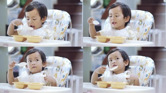亚洲男婴在高脚椅上吃胡萝卜。