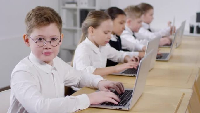 戴着眼镜的白人男生在计算机课上微笑