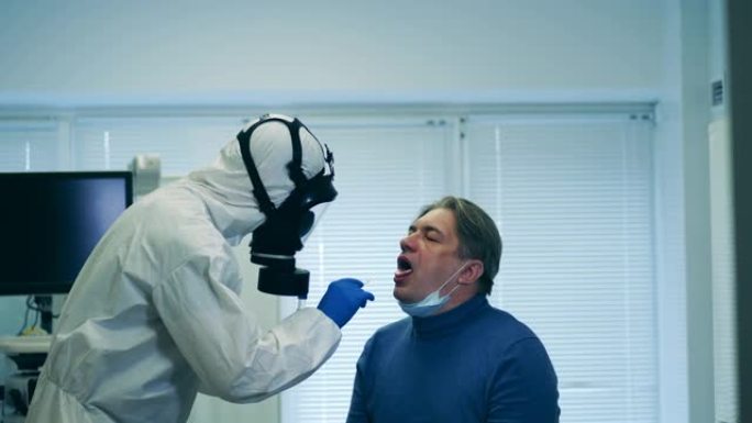 身着防溅服的医护人员正在取病人的唾液做测试。筛查患者covid-19、冠状病毒症状。