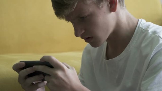 失望的十几岁的男孩玩电子游戏