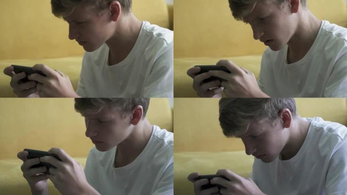 失望的十几岁的男孩玩电子游戏