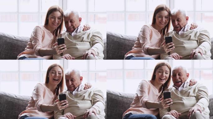 开朗的孙女用智能手机笑着拥抱爷爷