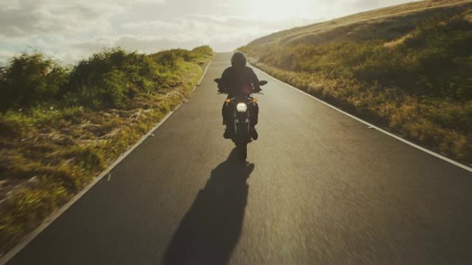 摩托车手在日落时沿着乡间小路骑行
