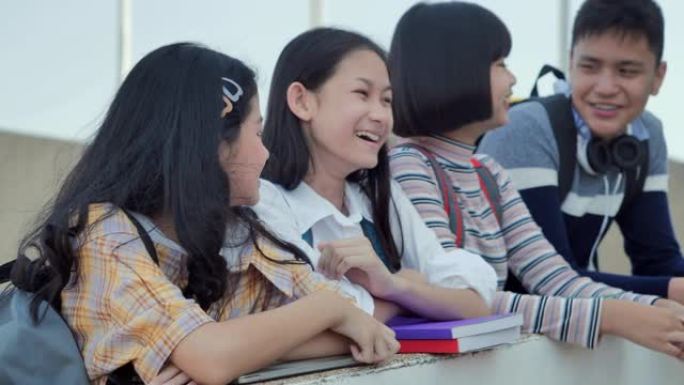 亚洲青少年学生四个人在学校学习后一起交谈。教育和学校观念。回到学校教育知识观念