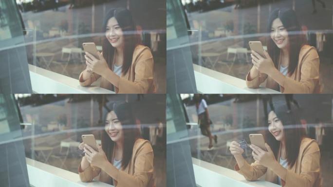 4k镜头亚洲妇女使用信用卡和手机在线购物的场景在百货公司的共同工作空间无现金，科技钱包和在线支付概念
