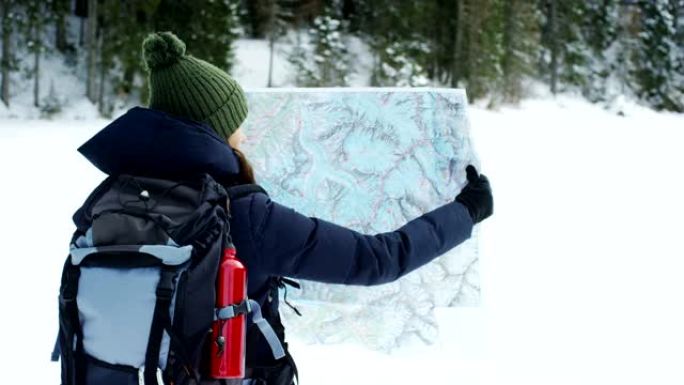 一个在山上度假的美丽女孩看着地图，以免迷路并了解地图的位置。