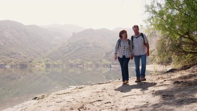 高级夫妇在山间湖边徒步旅行