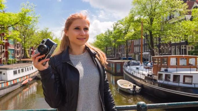 女人欣赏美丽的阿姆斯特丹城市，在美丽的晴天用老式复古模拟相机拍照