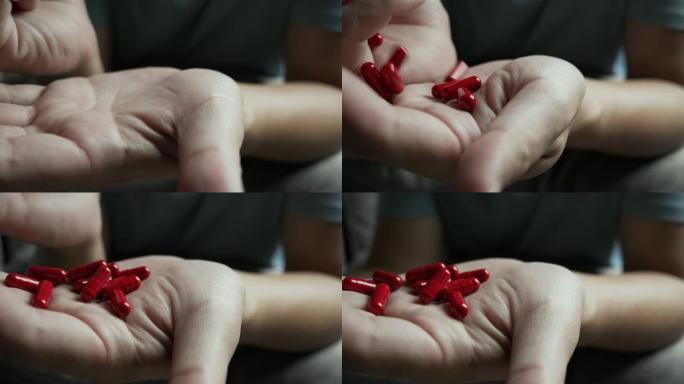 男子手将红色胶囊药丸滴在手上的4k镜头。医学概念