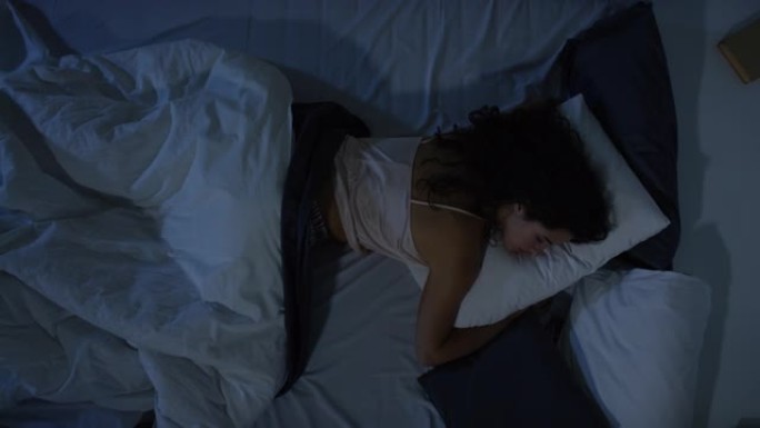 女人在黑暗中睡在床上的俯视图