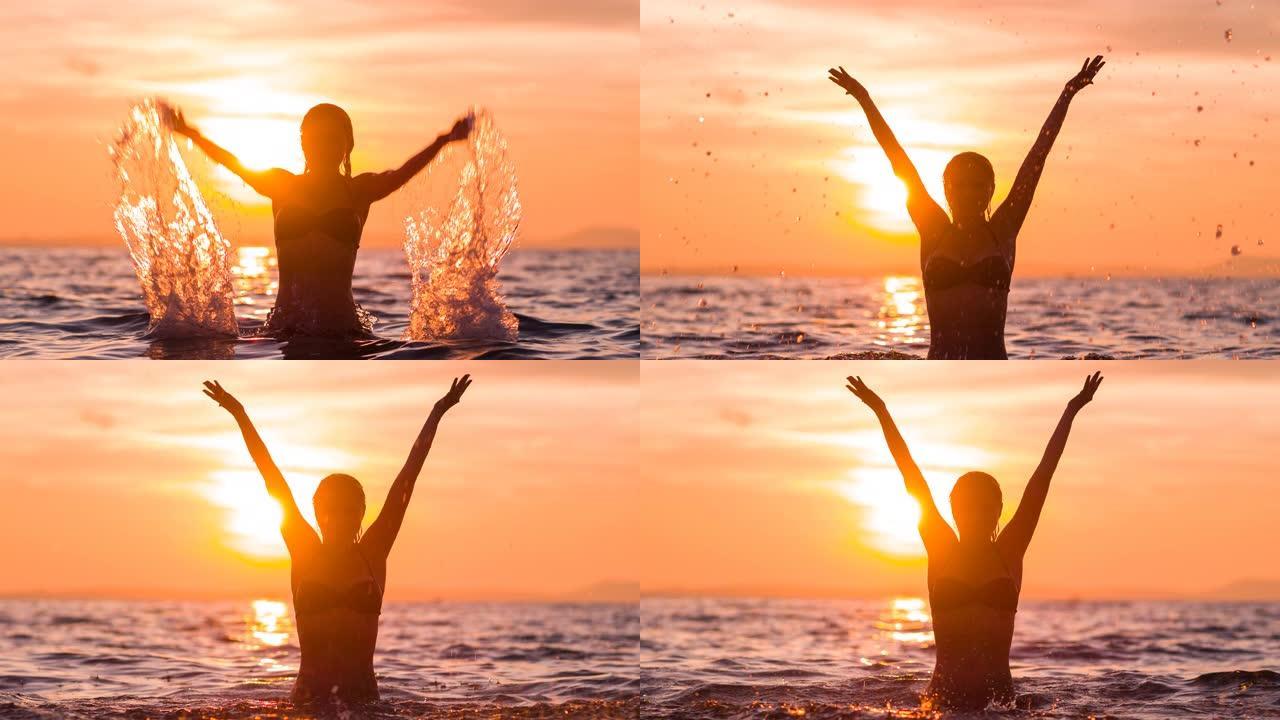 热带度假的幸福女人日落时在空中溅海水