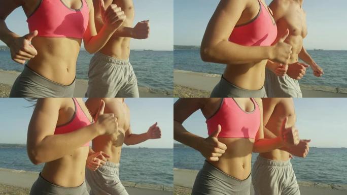 慢动作: 男性和女性腹肌在海边奔跑时的电影拍摄。