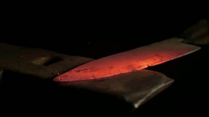 慢动作: 明亮的钢刀片被无法识别的工匠锻造。