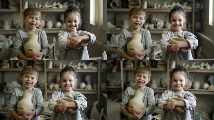 快乐的小孩在陶器工作室摆姿势