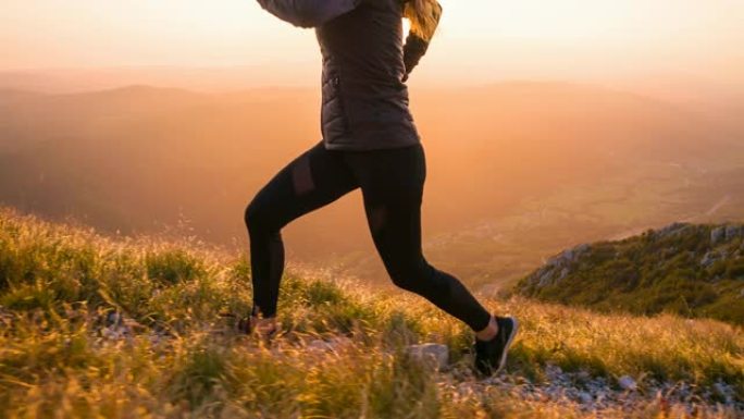 运动员保持健康的生活方式，在日落时分在多岩石的小径和草坡上奔跑
