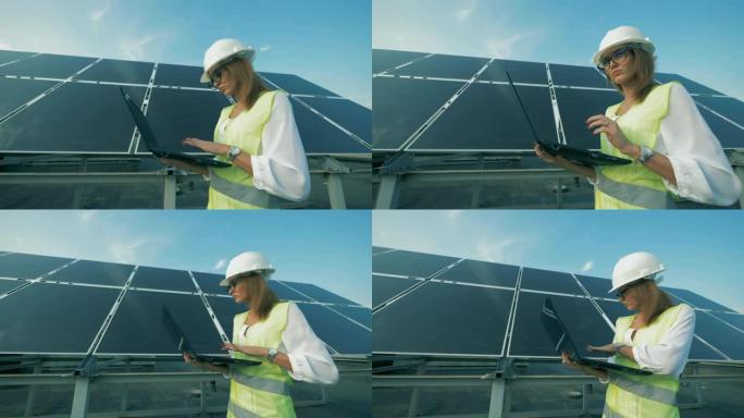 女建造师正带着电脑沿着太阳能电池板行走