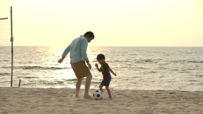 亚洲父子在日落背景下的海滩上踢球。慢动作。幸福家庭理念。
