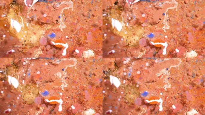 彩色丙烯酸涂料混合在美丽的图案中。珊瑚，橙色，红色和其他颜色的油墨水散布在表面并混合，创造出惊人的纹