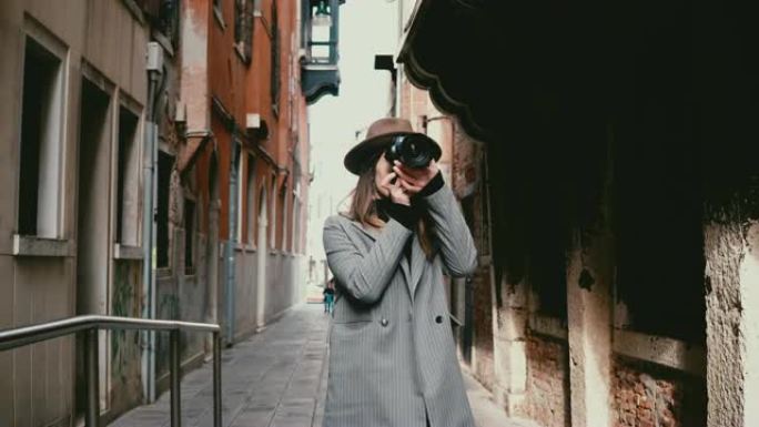 迷人的快乐职业记者女人在意大利威尼斯美丽的街道上与相机同行，拍照。