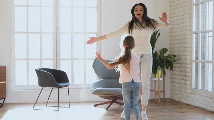 快乐的妈妈和孩子女儿在客厅跳舞跳跃
