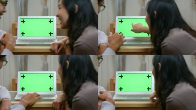 情侣爱在笔记本电脑上的绿屏上工作的特写镜头