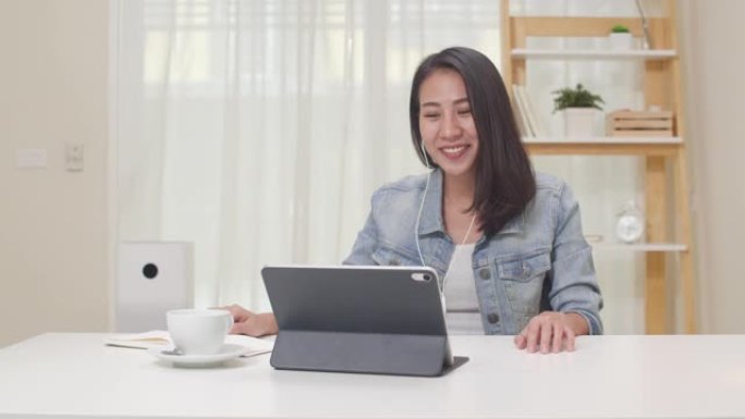 慢动作-自由职业商务女性休闲服使用平板电脑工作电话视频会议，客户在家里的客厅。