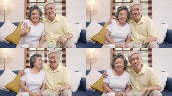 亚洲老年夫妇躺在家里客厅的沙发上，与孙子一起使用智能手机视频会议。享受时间生活方式老年家庭在家的概念