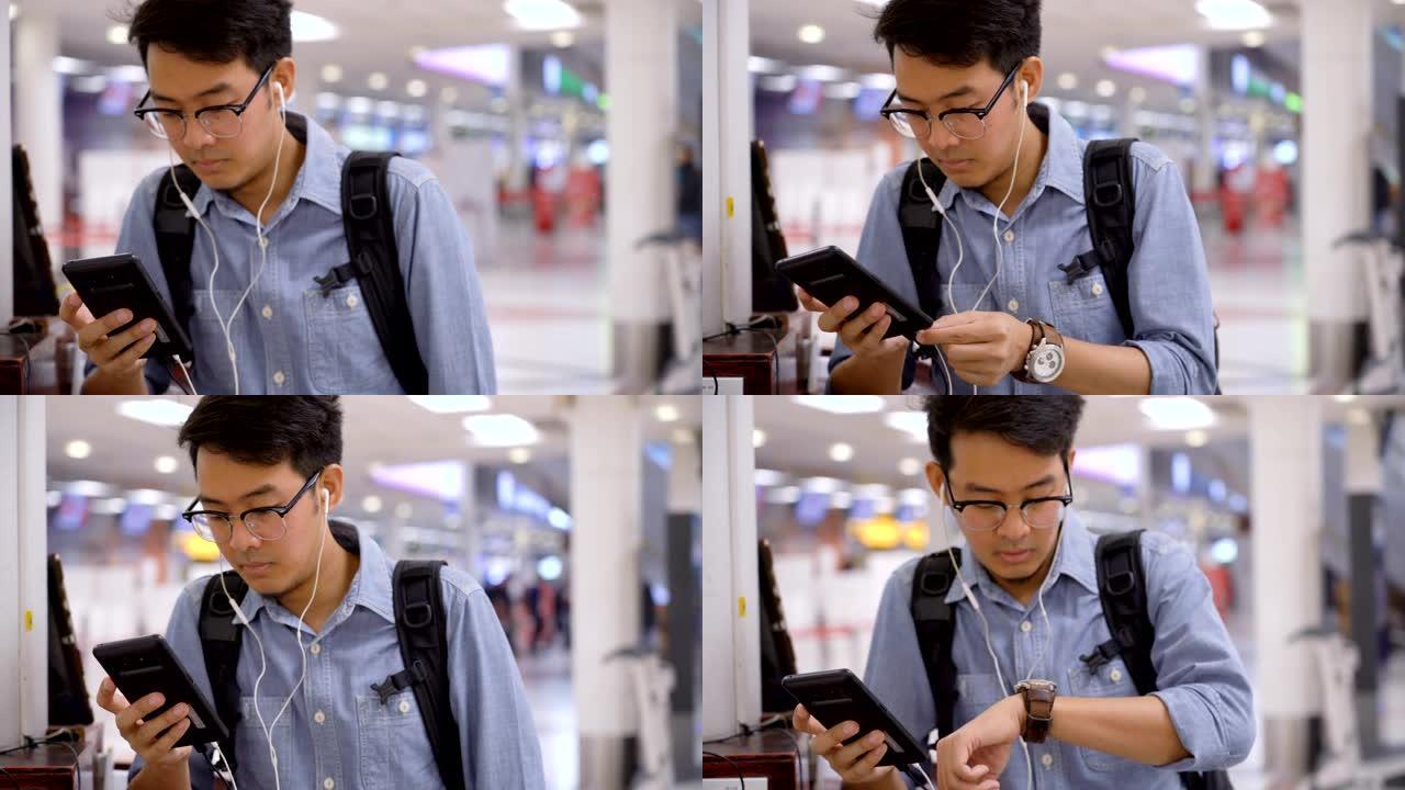 戴眼镜的亚洲男子在机场独自旅行时无事可做