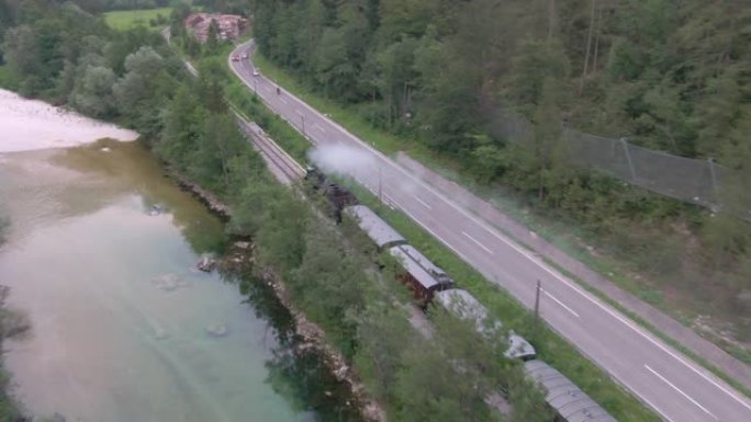 无人机: 博物馆蒸汽机车沿着美丽的河流和乡村道路行驶。