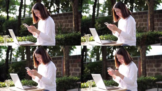 女性工作与她的笔记本电脑，使用智能手机和微笑在室外花园在家