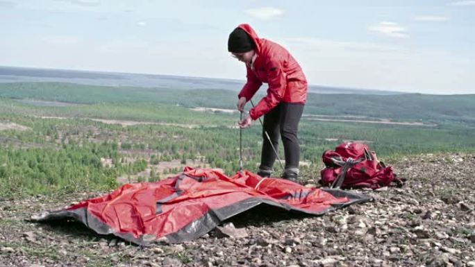 女人把杆子放进山顶的帐篷里