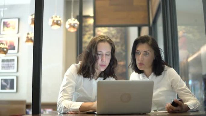 两名成年学生在咖啡馆使用笔记本电脑阅读tex