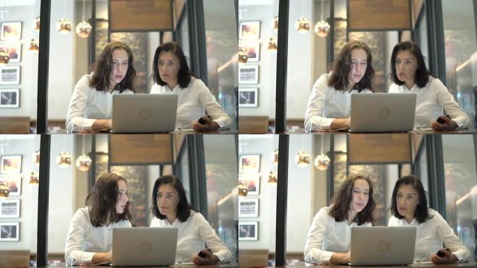 两名成年学生在咖啡馆使用笔记本电脑阅读tex