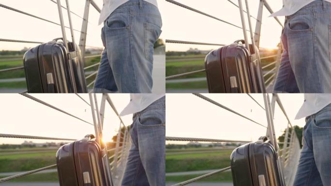 镜头耀斑: 游客在日落时等待出租车时握住他的手提箱。