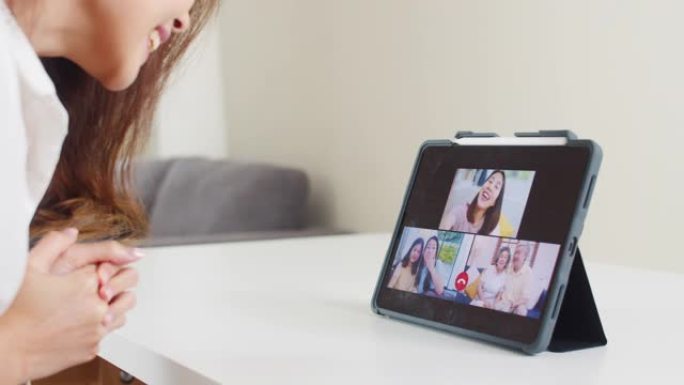 年轻的亚洲商界女性在客厅在家工作时使用平板电脑视频通话与家人交谈。