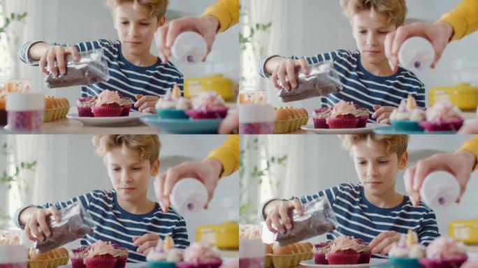 在厨房里: 一个聪明的小男孩在奶油蛋糕糖霜上撒上Funfetti的肖像。家庭一起煮松饼。可爱的孩子帮