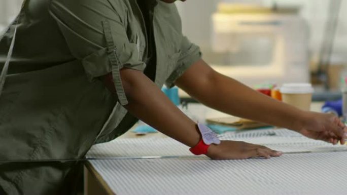 开朗的非洲女裁缝用粉笔在织物上绘画