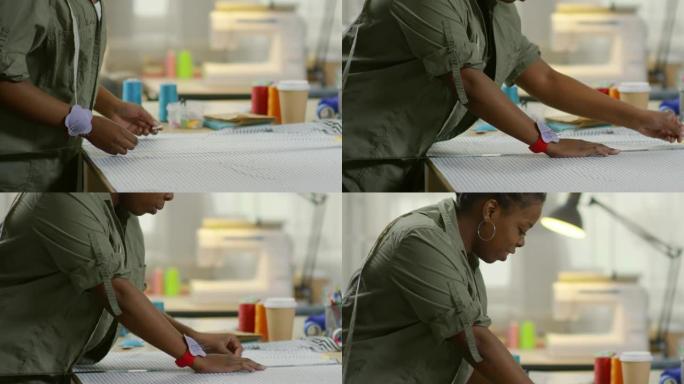 开朗的非洲女裁缝用粉笔在织物上绘画
