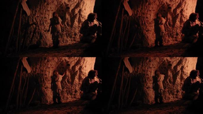 原始的史前尼安德特人的孩子穿着动物皮在晚上在墙上画动物和摘要。用岩画、岩画创造第一个洞穴艺术。拍摄后
